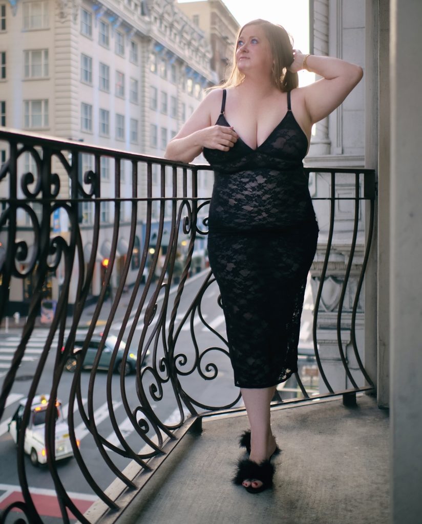 Gracie Blue in a black dress on a city balcony